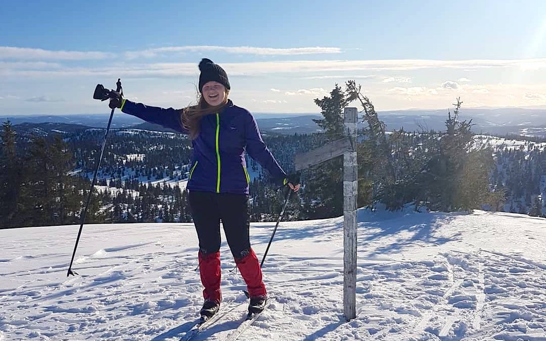 Tienermeisje op luchten op een besneeuwde heuvel in Noorwegen